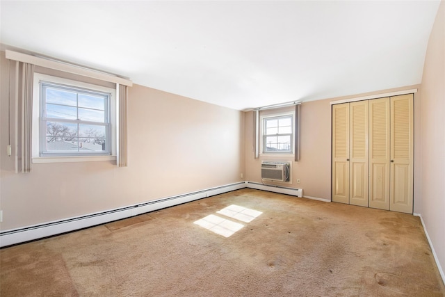 unfurnished bedroom with baseboards, a wall mounted air conditioner, baseboard heating, carpet flooring, and a closet