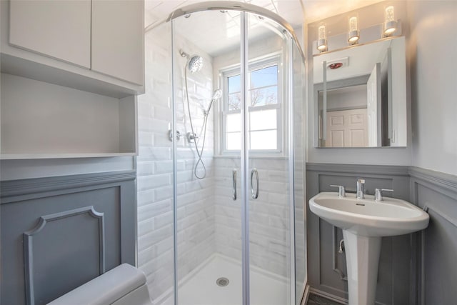 full bath featuring a wainscoted wall, a shower stall, and a decorative wall