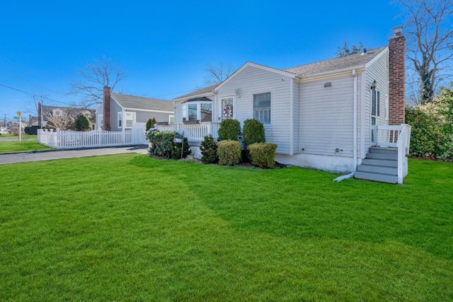 view of front facade featuring a chimney, a front yard, and fence