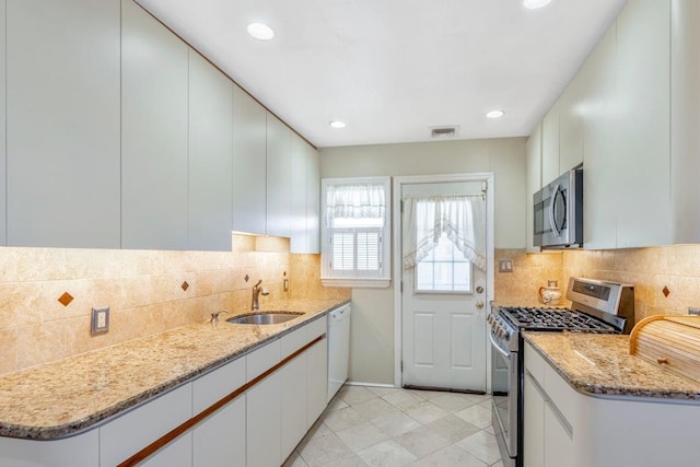 kitchen with stainless steel appliances, a sink, visible vents, white cabinets, and light stone countertops