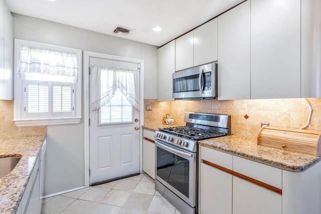 kitchen featuring visible vents, white cabinets, decorative backsplash, light stone countertops, and stainless steel appliances