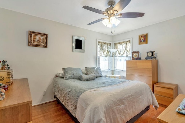 bedroom with a ceiling fan, baseboards, and wood finished floors