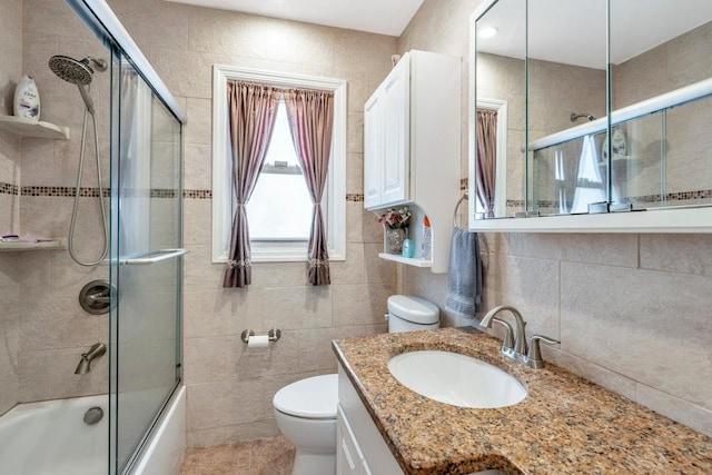 full bathroom with toilet, vanity, tile walls, combined bath / shower with glass door, and decorative backsplash