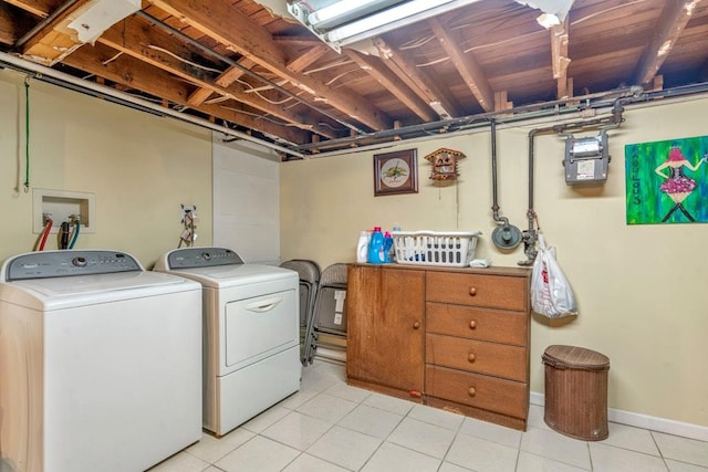 clothes washing area featuring light tile patterned floors, laundry area, independent washer and dryer, and baseboards