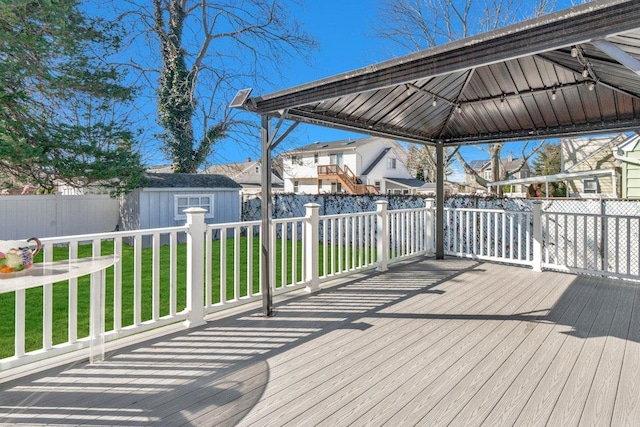 wooden deck with a yard, a gazebo, a shed, a fenced backyard, and an outdoor structure