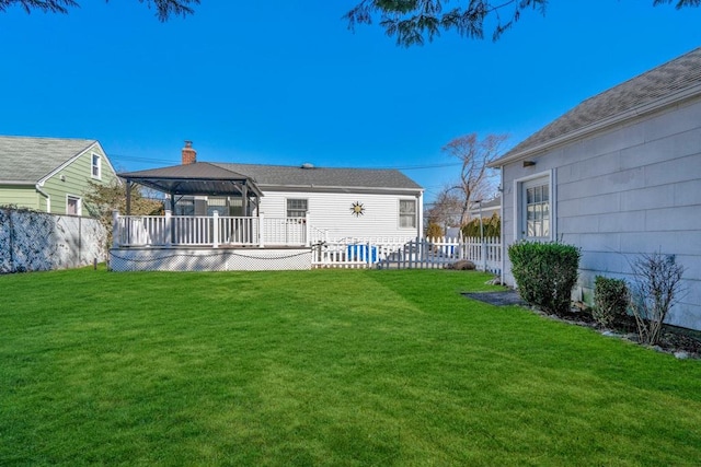 back of house featuring a chimney, a gazebo, fence, a deck, and a yard