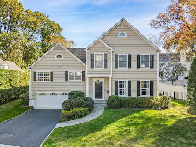 view of front facade featuring an attached garage, aphalt driveway, a front yard, and fence