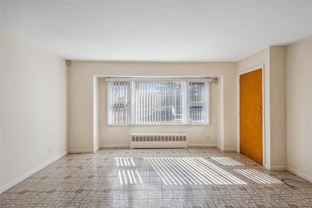 unfurnished room with radiator heating unit and baseboards