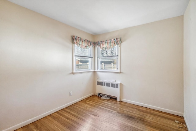 unfurnished room featuring radiator, baseboards, and hardwood / wood-style flooring