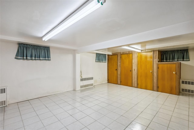 finished below grade area featuring radiator and light tile patterned flooring