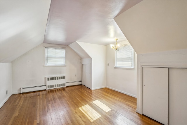 additional living space with a baseboard heating unit, radiator, vaulted ceiling, and hardwood / wood-style flooring