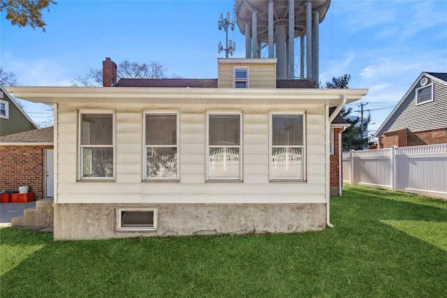 back of property with a chimney, fence, and a yard