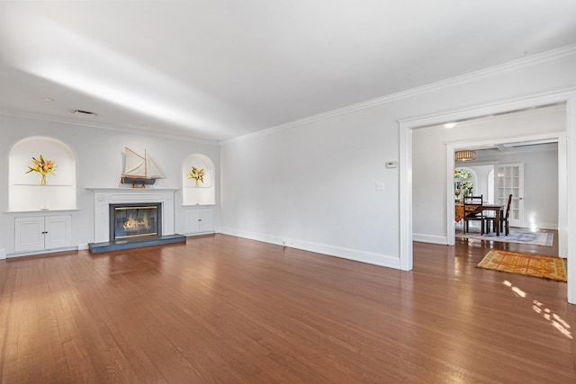 unfurnished living room featuring visible vents, ornamental molding, a glass covered fireplace, wood finished floors, and baseboards