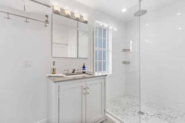 full bathroom featuring a tile shower and vanity