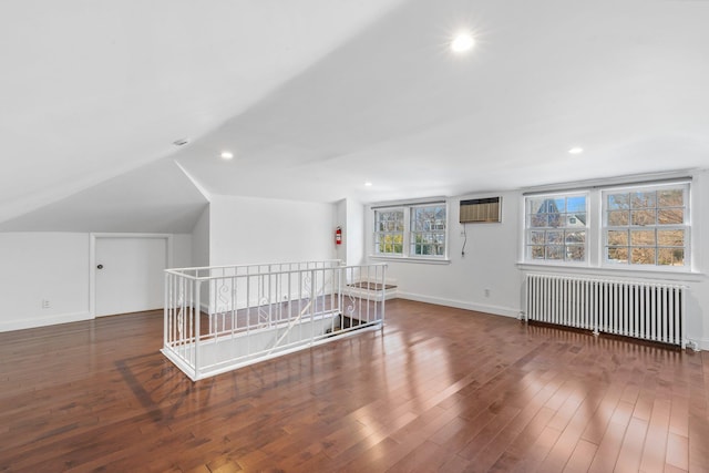 bonus room with lofted ceiling, a wall unit AC, dark wood-type flooring, baseboards, and radiator