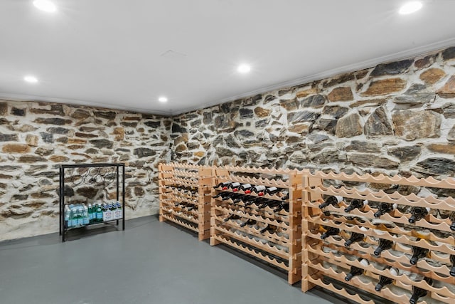 wine cellar with ornamental molding, finished concrete floors, and recessed lighting