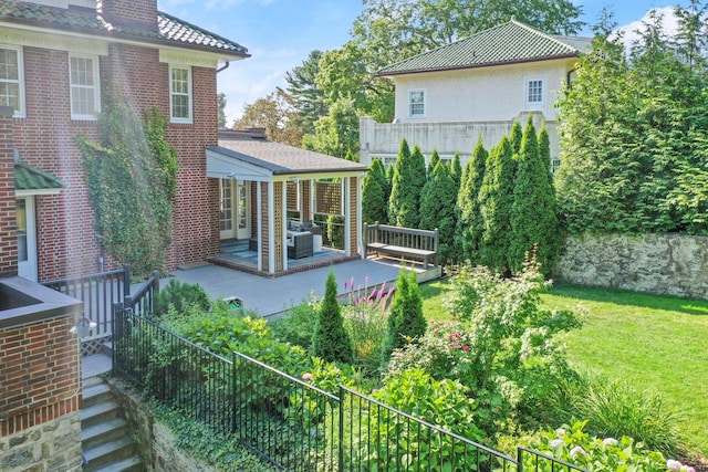 back of property with fence, a deck, a lawn, and stucco siding