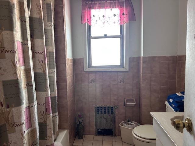 bathroom featuring tile patterned flooring, toilet, vanity, tile walls, and radiator