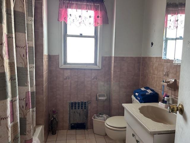 bathroom with tile patterned flooring, toilet, vanity, tile walls, and radiator