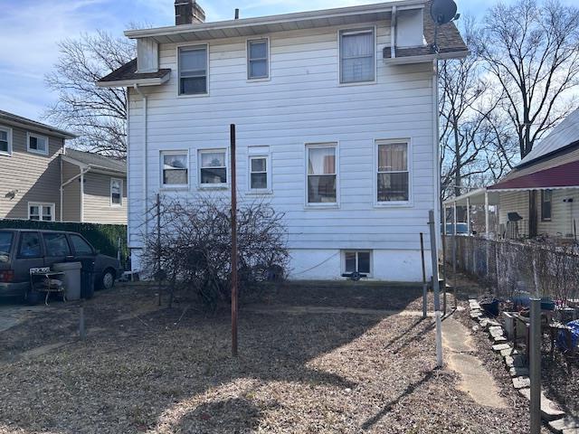 back of house with fence and a chimney