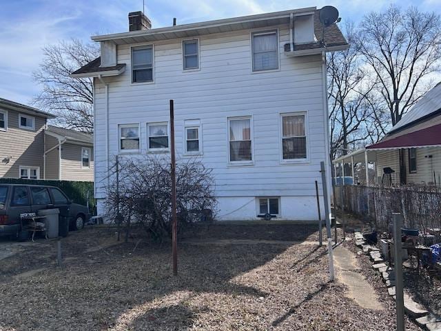 rear view of property with fence and a chimney