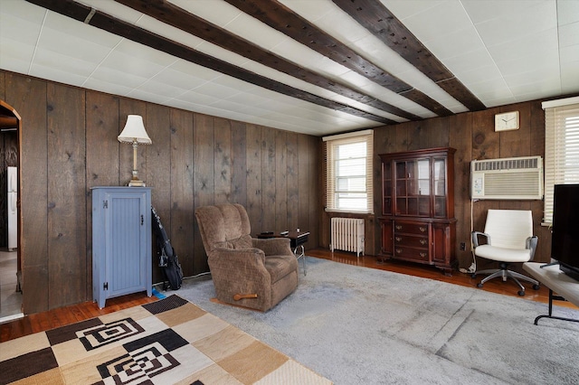 unfurnished room featuring radiator, wooden walls, wood finished floors, and a wall mounted AC