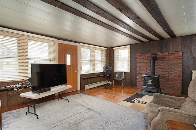 living room with a baseboard heating unit, wood finished floors, a wood stove, and wooden walls