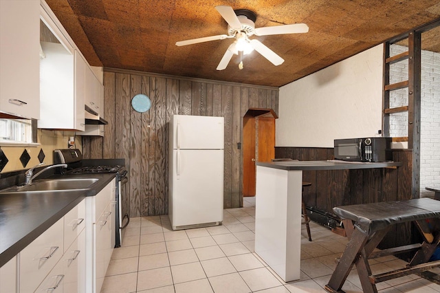 kitchen featuring dark countertops, freestanding refrigerator, stainless steel range with gas cooktop, black microwave, and a sink