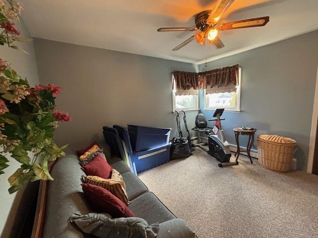 workout room with a baseboard heating unit, ceiling fan, and carpet flooring