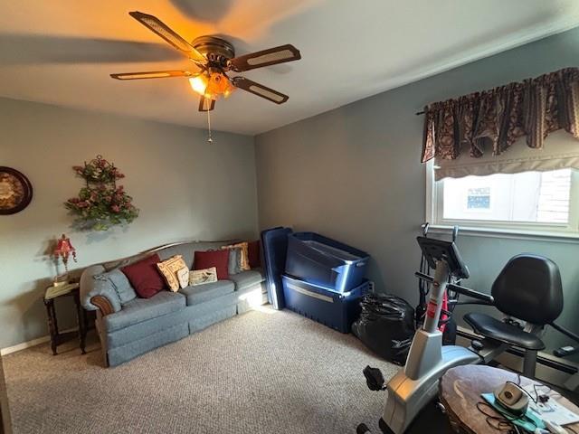 carpeted living room featuring baseboards and a ceiling fan