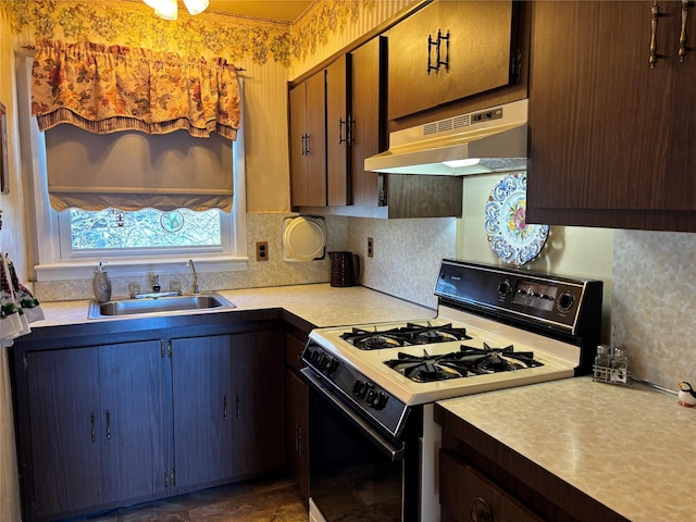 kitchen featuring range with gas stovetop, light countertops, backsplash, a sink, and under cabinet range hood