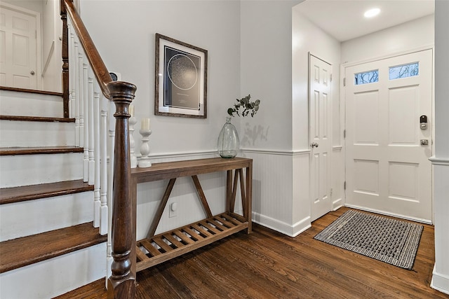 entryway featuring a wainscoted wall, stairway, and wood finished floors