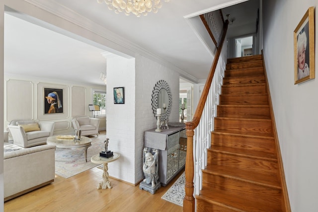 stairway with wood finished floors and ornamental molding