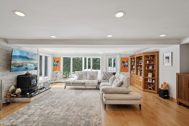 living area with a wood stove, recessed lighting, light wood-type flooring, and ornamental molding