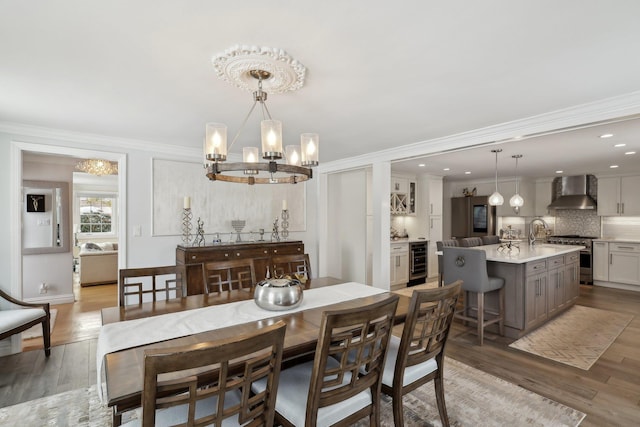 dining room with beverage cooler, a chandelier, crown molding, and light wood-type flooring