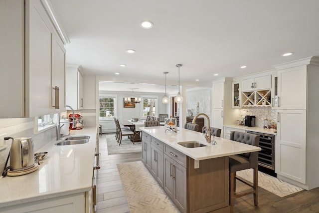 kitchen with decorative backsplash, wood finished floors, beverage cooler, and a sink