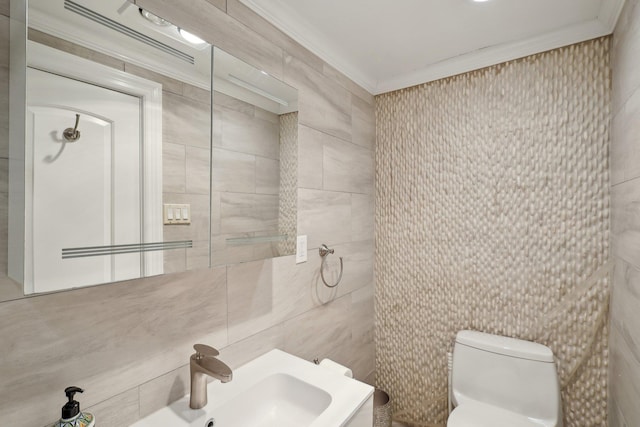 half bath featuring a sink, toilet, tile walls, and ornamental molding