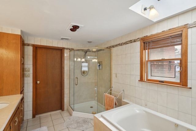 bathroom with visible vents, a garden tub, tile walls, and a shower stall