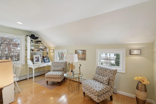 sitting room with a wealth of natural light, lofted ceiling, and hardwood / wood-style flooring