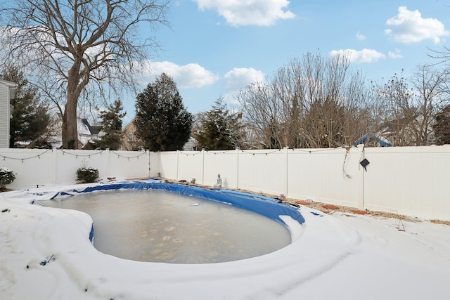 snow covered pool featuring a fenced backyard