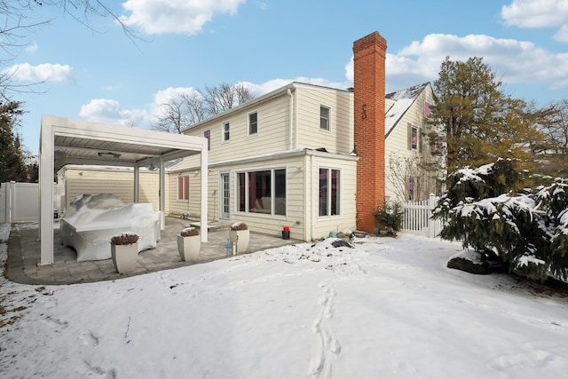 snow covered property with a chimney and fence