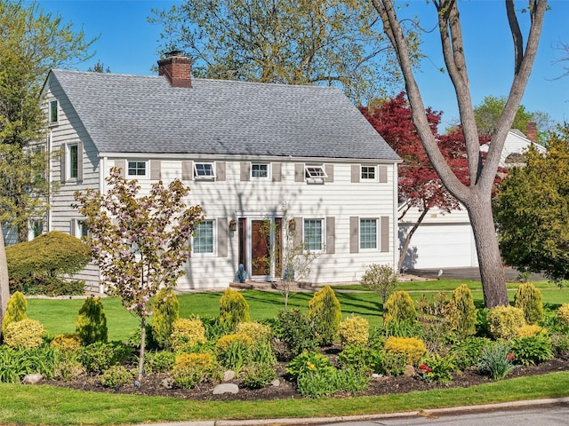 colonial house with roof with shingles, a chimney, and a front lawn