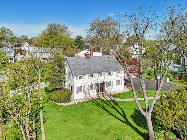 exterior space with a shingled roof, a chimney, and a front yard