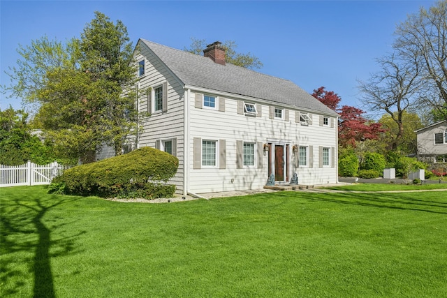 colonial inspired home featuring fence, a chimney, and a front yard