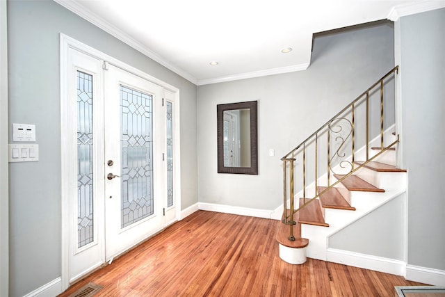 foyer with crown molding, stairs, baseboards, and wood finished floors