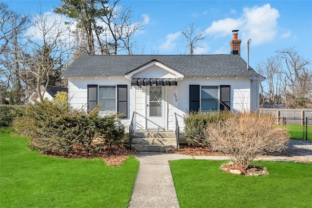 bungalow featuring entry steps, a chimney, fence, and roof with shingles