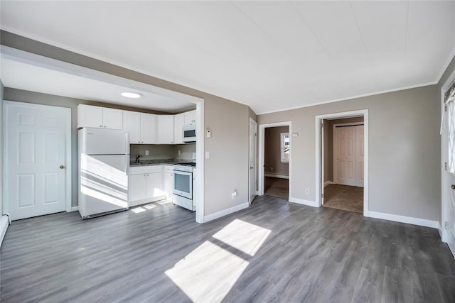 kitchen with white appliances, baseboards, white cabinets, and dark wood-type flooring