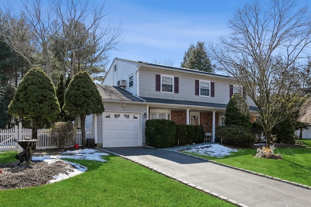 traditional-style house featuring a garage, aphalt driveway, fence, a front lawn, and brick siding