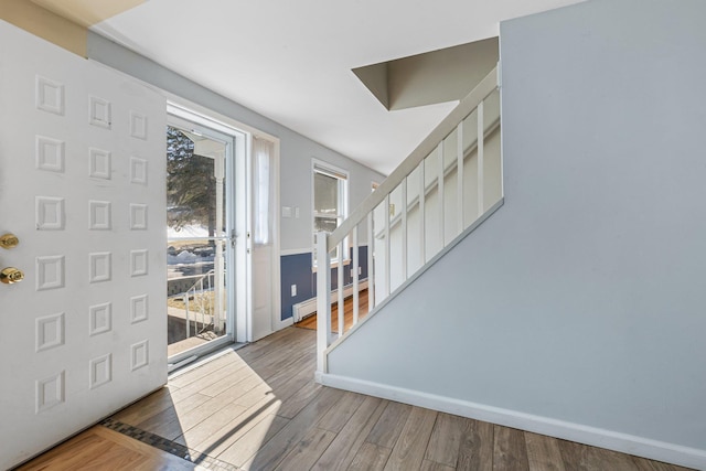 foyer featuring a baseboard radiator, stairway, baseboards, and wood finished floors