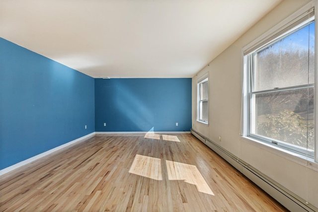 unfurnished room with a baseboard radiator, baseboards, and wood finished floors